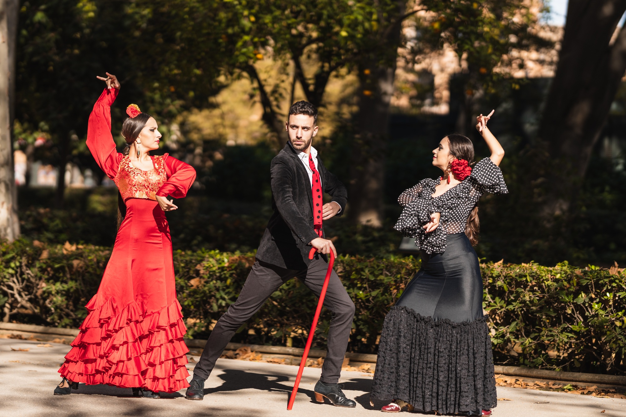 Inicio 1 Three hispanic people dancing flamenco next to the gardens of a square