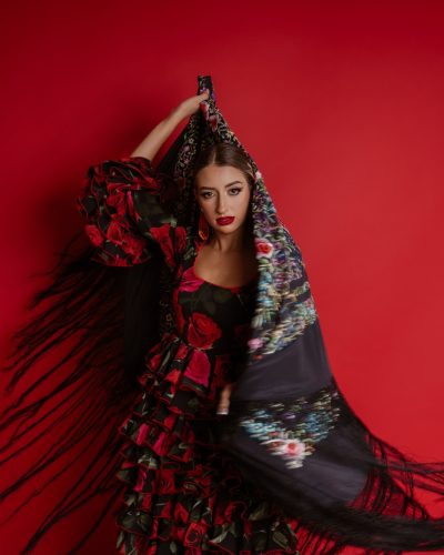 Young woman in traditional flamenco dress against red background Young woman in traditional flamenco dress against red background